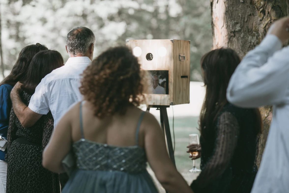 La borne photo NEXG en bois pendant une réception, entourée des invités